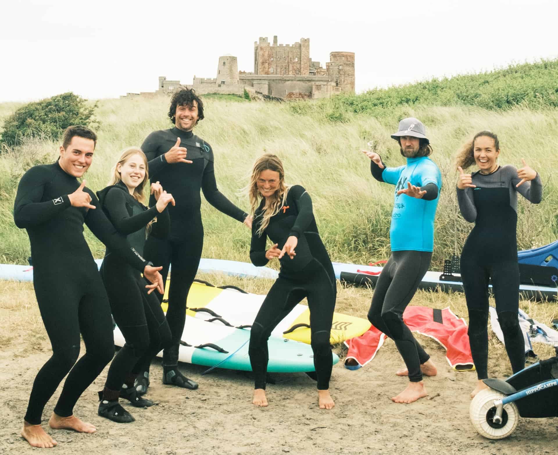 NE Surf school and Surfability pose for a picture infront of Bamburgh Castle with adaptive surfing equipment