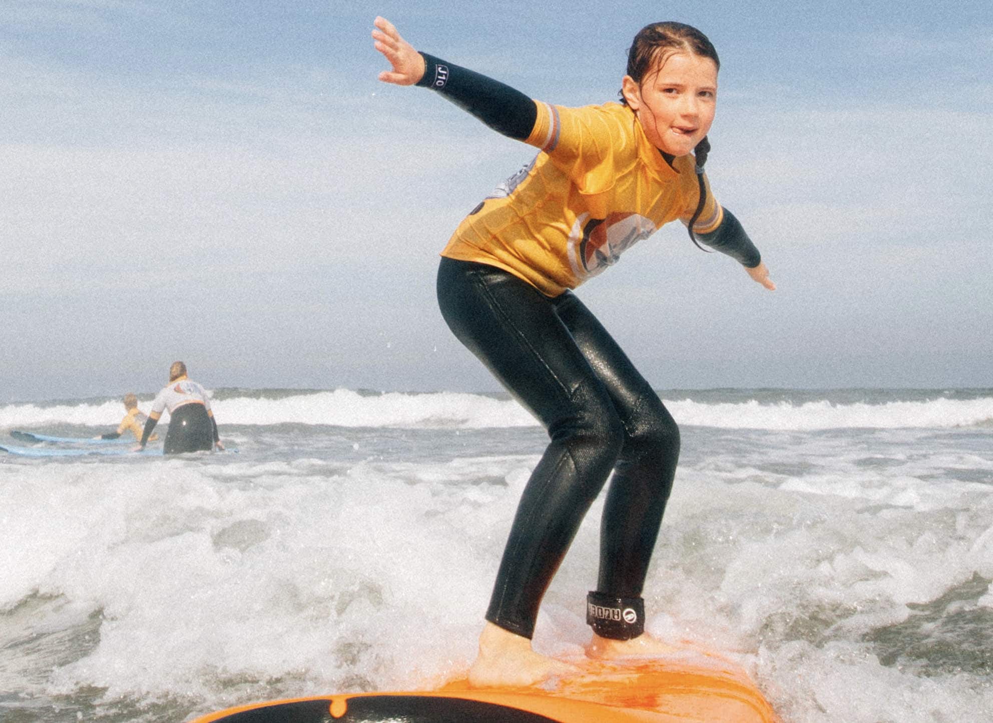 Young girl surfing a foam surfboard at Bamburgh beach